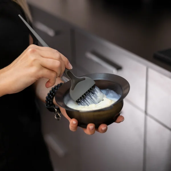 Une femme se coiffe avec un peigne, utilisant un toner pour cheveux.